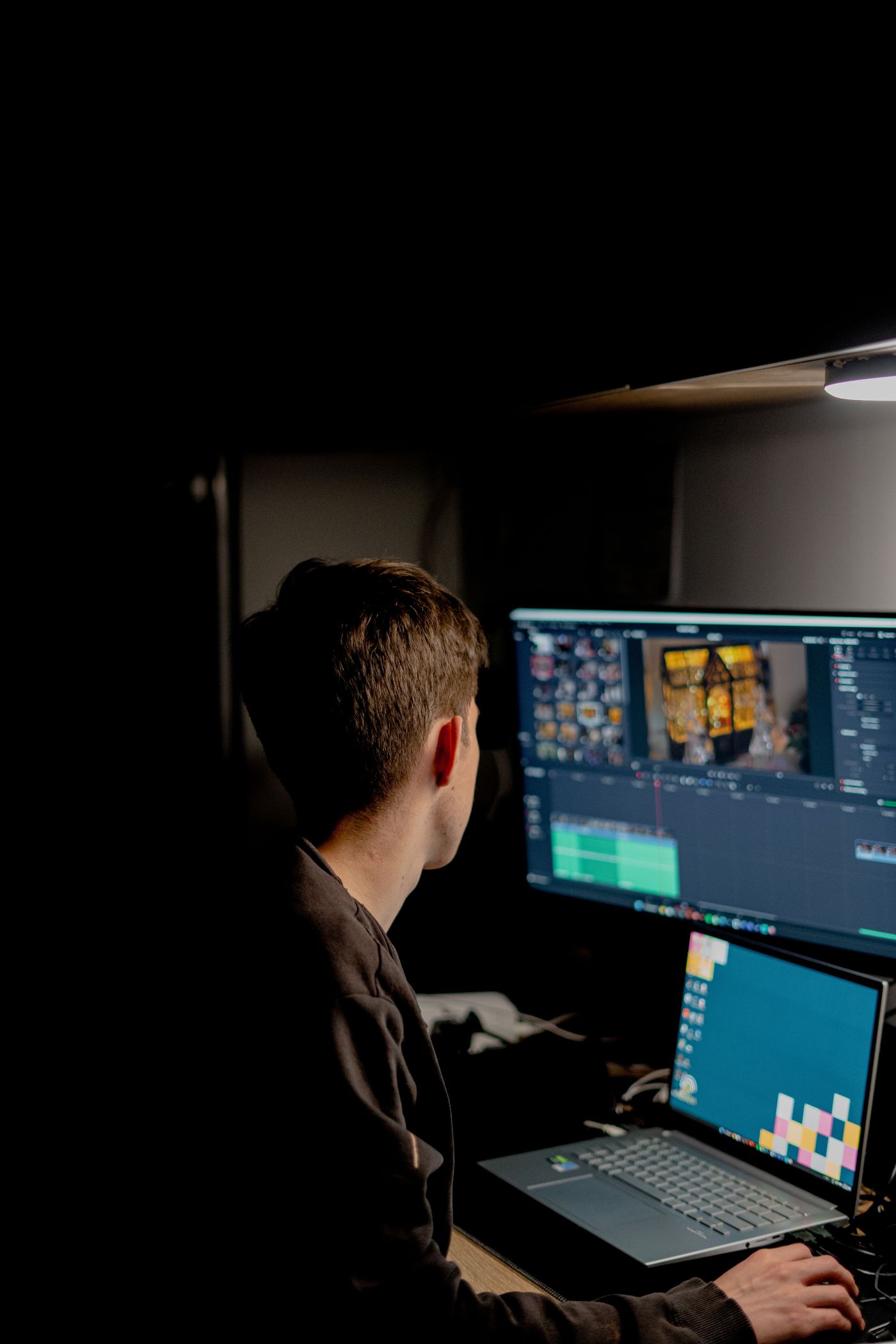 A developer working at a multi-screen desk late in the evening